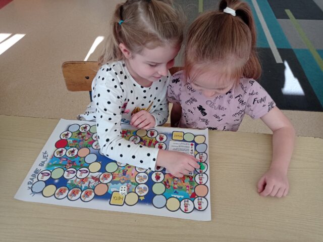 Zosia i Zuzia grają w grę planszową „W krainie bajek”.