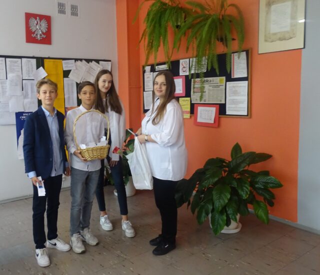 Przedstawiciele Samorządu Uczniowskiego częstują pracowników szkoły drobną słodkością. 