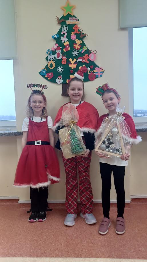Dziewczynki z uśmiechem na twarzy przekazują prezenty od św. Mikołaja.