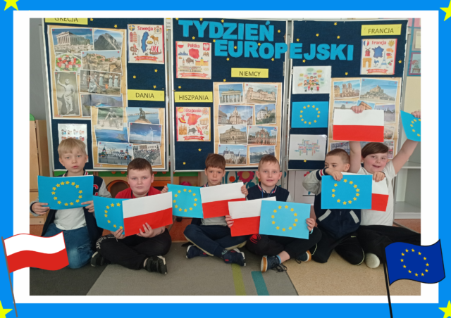 Tydzień Europejski w świetlicy. Dzieci na tle dekoracji tematycznej prezentują zrobione samodzielnie flagi.