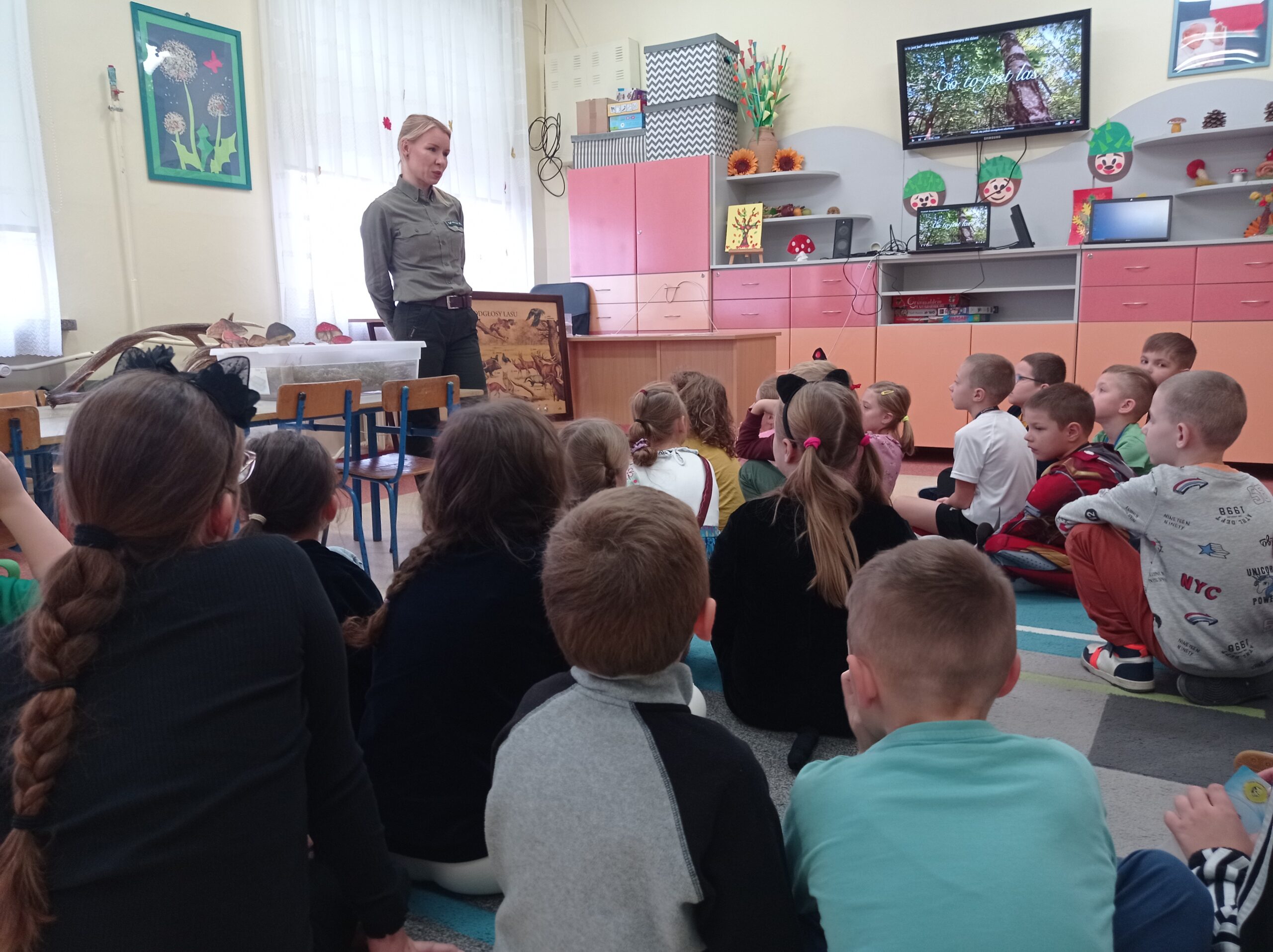 Zajęcia edukacyjne. Pani leśnik opowiada uczniom o zwierzętach zamieszkujących polskie lasy.