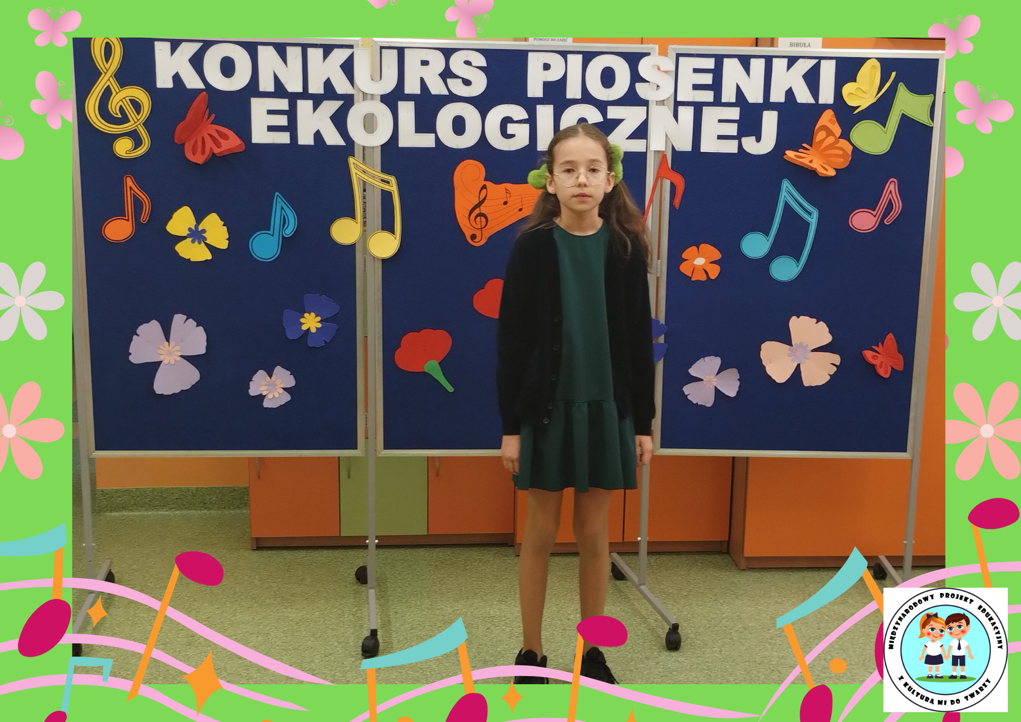 Dziewczynka z kl. III c stoi na tle dekoracji i interpretuje piosenkę pt. „Kolorowy wiatr”.